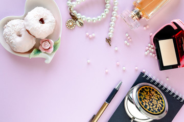 Fashion blogger workspace with laptop and female accessory, cosmetics products on pale pink table. Sweets, donuts, macaroons and gifts for the holiday Valentine's Day. flat lay, top view