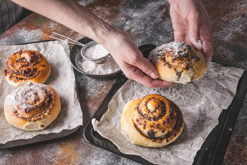 Female hands hold a fresh sweet homemade cinnamon roll with chocolate cream. Scandinavian cuisine. Hyugge style