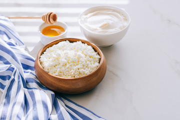 Healthy breakfast of cottage cheese with sour cream and honey on a marble table