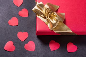 Red gift box with gold ribbon on black background, copy space
