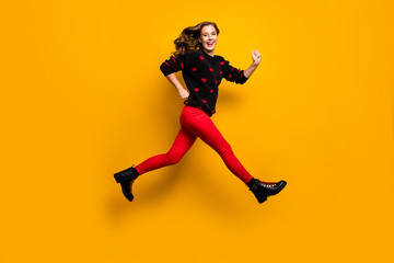 Fototapeta na wymiar Full length profile photo of pretty lady jumping up high speed rushing low prices shopping wear hearts pattern sweater red trousers boots isolated yellow color background