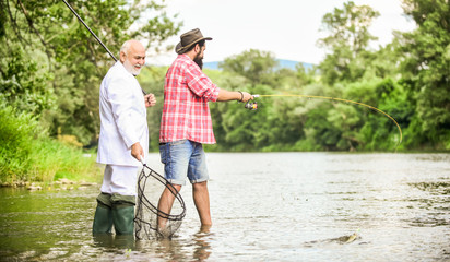 Family day. Fishing team. Friends fishing. Hobby and recreation. Summer vacation. Perfect weekend. Successful catch. Relax in natural environment. Elegant bearded man and brutal hipster fishing