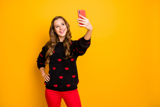 Photo of amazing pretty lady hold telephone hands making funny positive energetic selfies wear hearts pattern pullover red pants isolated yellow color background