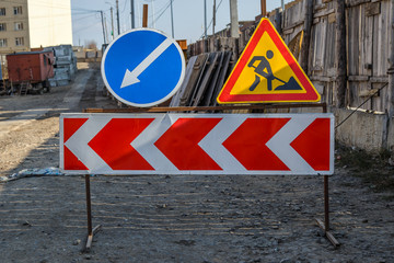 Work in progress. Roadworks, road signs. Men at work. Some signs signage for work in progress on urban street. Barriers and road signs. Silhouette of a worker at work. Right arrow.