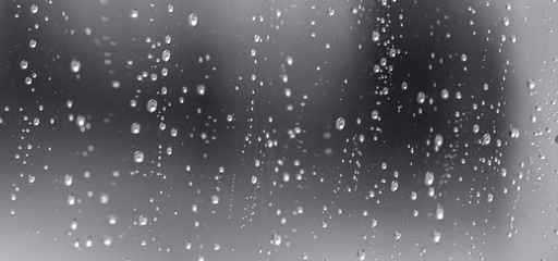 Rain waterdrops on a black dramatic window glass. Autumn  bokeh depression background. Rain pattern.