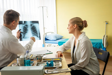 Doctor explaining lungs x-ray to women patient in clinic or Doctor in the office examining an x-ray...