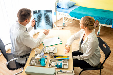 Obraz premium Doctor explaining lungs x-ray to women patient in clinic or Doctor in the office examining an x-ray and discussing with a patient