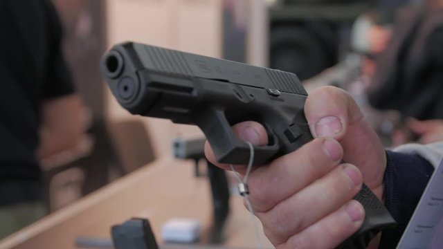 Man holding a gun buys chooses pistol in a military weapon store hands closeup