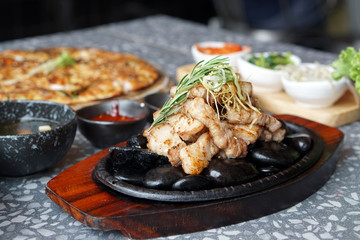Grilled pork belly served on hot stones, Topped with chopped spring onions and rosemary leaf, Korean BBQ style, The national street food of Korea.