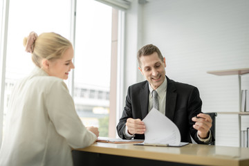 happy Boss businessman talking about report with woman employee and sign signature in document on...