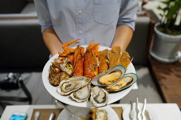 Plate of various types of seafood set, steamed rock lobster, baby lobster, New Zealand mussel, blue crab and fresh pacific oyster, Dinner buffet seafood night. © Thaweerat