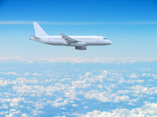 Plakat large white passenger plane flies high above the clouds
