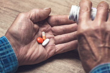 Many multi-colored pills in a Senior's hands