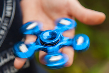 close up view of hanf of boy on which blue spinner is spinning