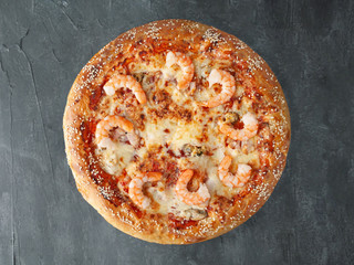 Italian pizza. With tiger prawns, squid, mussels, tomato sauce, mozzarella cheese. Wide side. View from above. On a gray concrete background. Isolated.