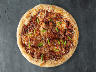 Italian pizza. Smoked chicken, Mozzarella cheese, Sulguni, tomato sauce, spices and green onions. Wide side. View from above. On a gray concrete background. Isolated.