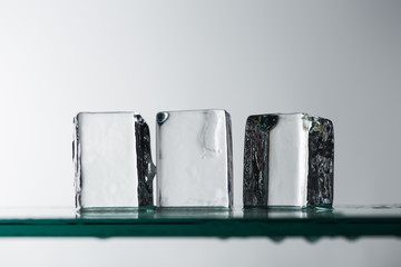 selective focus of melting transparent clear square ice cubes isolated on white