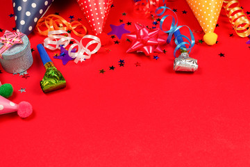 Festive golden and purple stars of confetti  and a present, birthday caps on a red background.