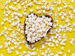 Top view on a wooden bowl in the form of a heart with popcorn