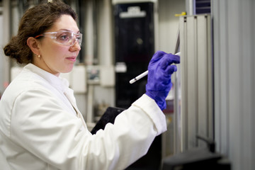 Lab assistant woman in white coat records results in laboratory