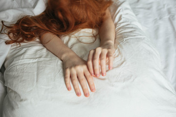 Red-haired girl's hands on the pillow