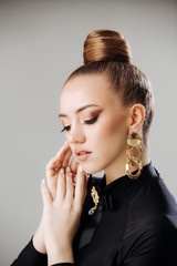 Beautiful woman model with golden earrings. Beautiful woman with luxurious make-up and manicure. Girl with expensive jewelry. Fashionable hairstyle high bun