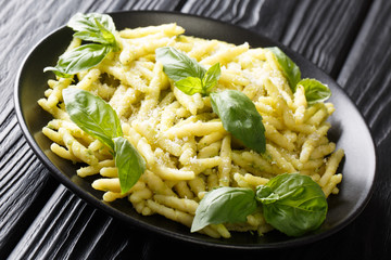 Serving of trofie pasta with green basil pesto and parmesan cheese close-up in a plate. horizontal