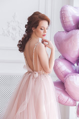 Beautiful woman holding pink balloons heart shaped. Model female on st. Valentine`s background.