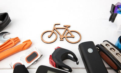 A lot of different bicycle accessories lying on wooden table around a little bicycle icon