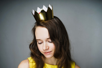 a teenage girl modestly lowered her eyes down, on her head a toy gold crown