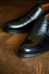 black leather shoes on a brown background