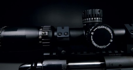 4k pan of a black sniper rifle scope with a dark neutral background