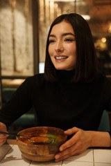 Beautiful young brunette woman sitting at the cafe table