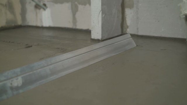 Builders leveled the floor with a mortar and a mixture. Fill screed floor repair and furnish, shallow dof. The finished result, the solution is aligned on the floor.