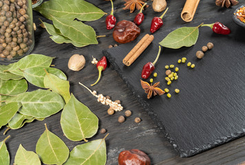 Stone board with various spices on a dark background