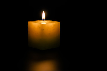 A lighted candle on a neutral black background, ideal for text application