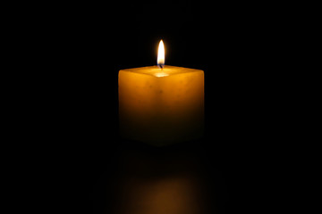 A lighted candle on a neutral black background, ideal for text application