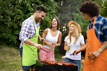 Naklejka na ściany i meble Group of happy young friends having barbecue party, outdoors