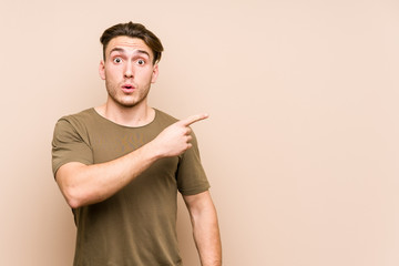 Young caucasian man posing isolated pointing to the side