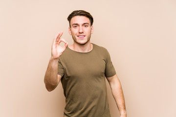 Young caucasian man posing isolated cheerful and confident showing ok gesture.