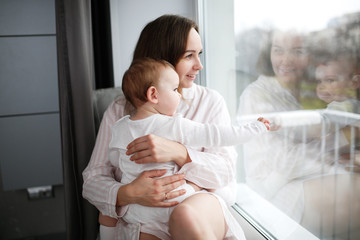 Tender mom and baby together near window lifestyle