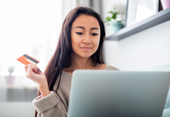 Asian girl making online payment using laptop for shopping at home