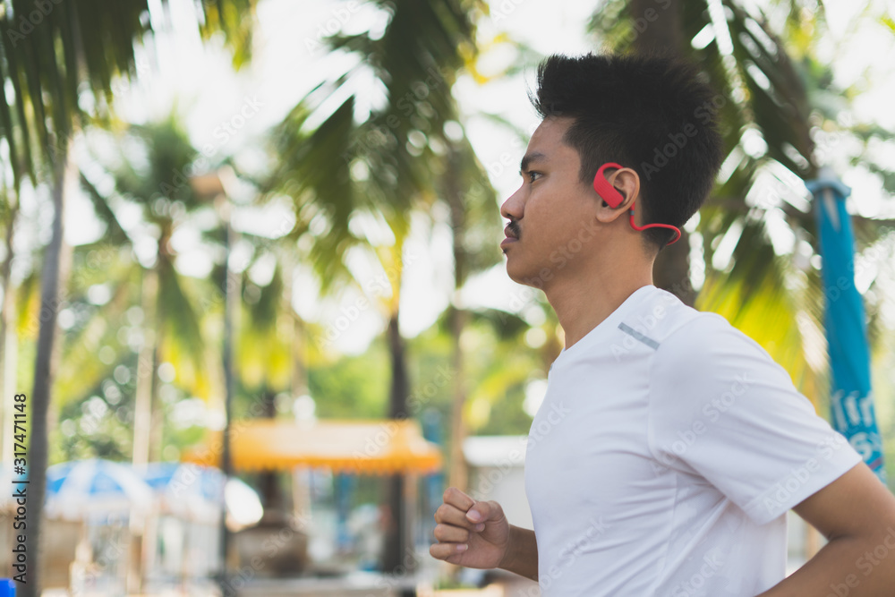 Poster fit young man running on beach with wireless headphone