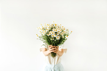 Young pretty woman hold in hands bouquet of white chamomile daisy flowers on white background.
