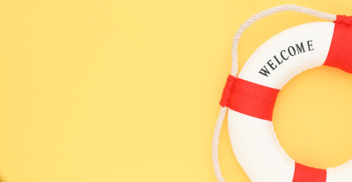 Lifebuoy with the word welcome on a yellow background. Time for summer vacation, conceptual photo with empty space.