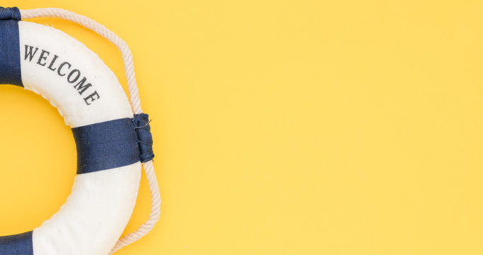 Lifebuoy with the word welcome on a yellow background. Time for summer vacation, conceptual photo with empty space.