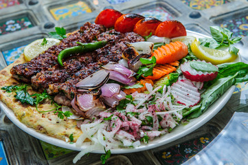 Healthy barbecue different meat with vegetables and sauce. served with a black plate. close up view on a light background. Arabic food.