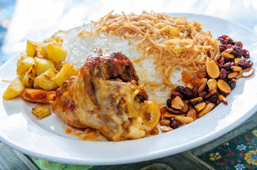 Plate of yellow rice topped with mutton meat and potatoes.