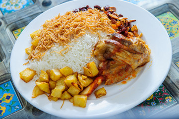Plate of yellow rice topped with mutton meat and potatoes.