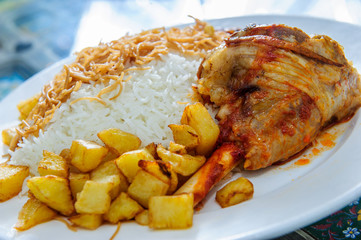 Plate of yellow rice topped with mutton meat and potatoes.